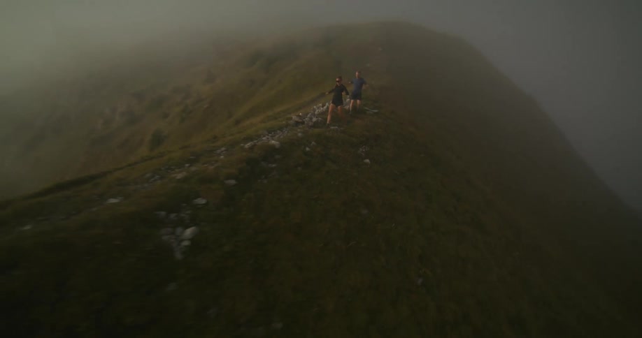 Two people running down a steep foggy hill