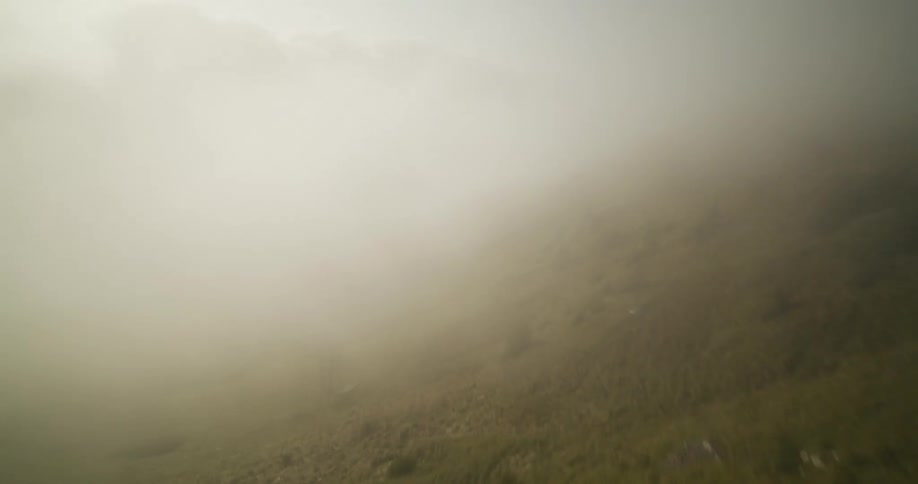 Two people running on top of a hill with the sky covered by a thick cloud
