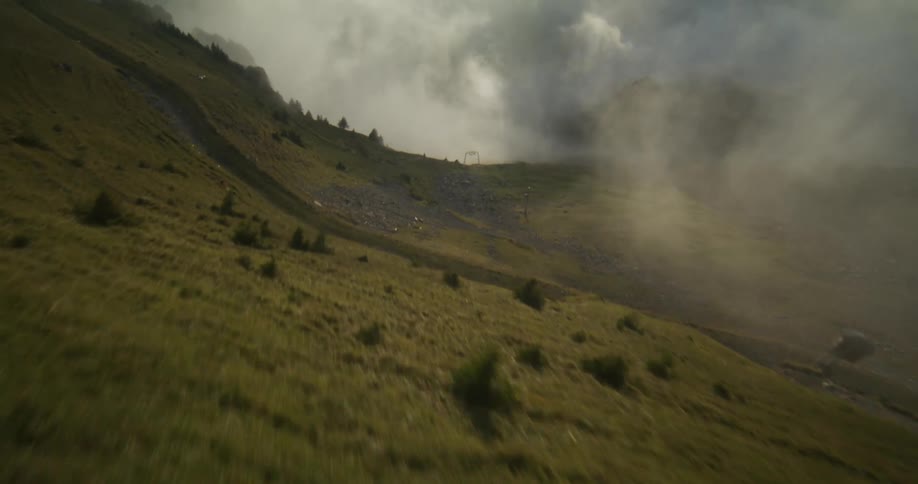 The top of hills with short grasses are covered in fog