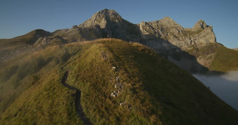 Two people running on top of a hill on a sunny morning