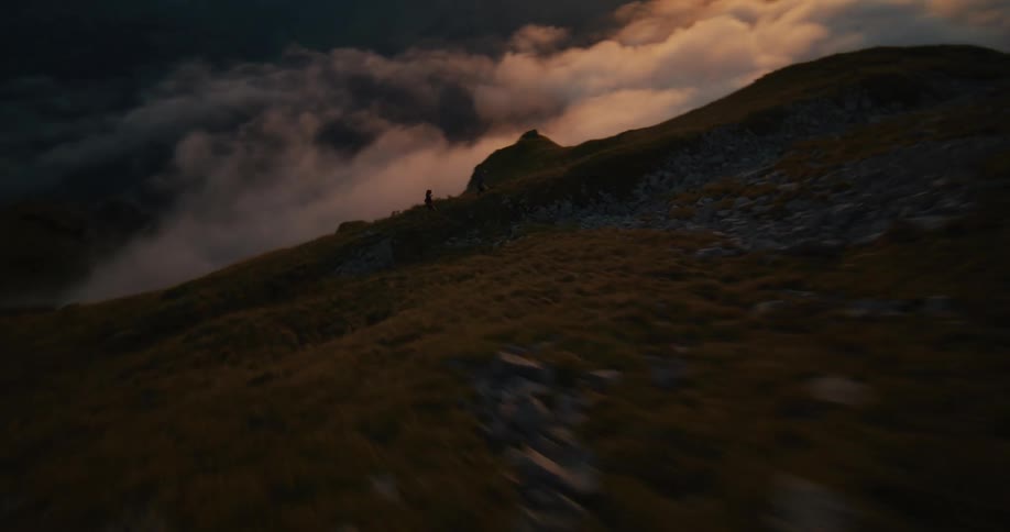 Two people running on a hill in the mountain during sun down