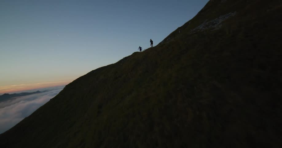 The silhouette of two people running on a large mountain