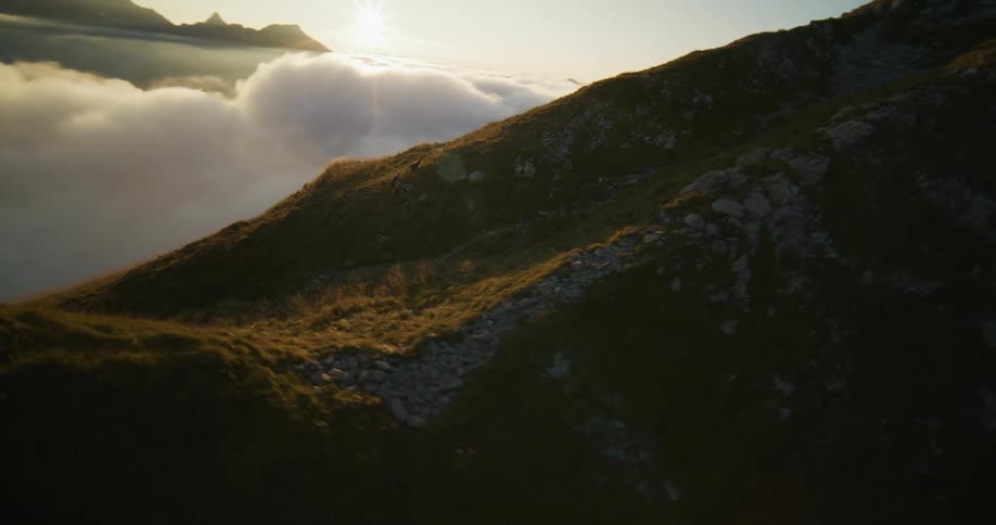 Two people are climbing a high mountain and behind them there are many clouds