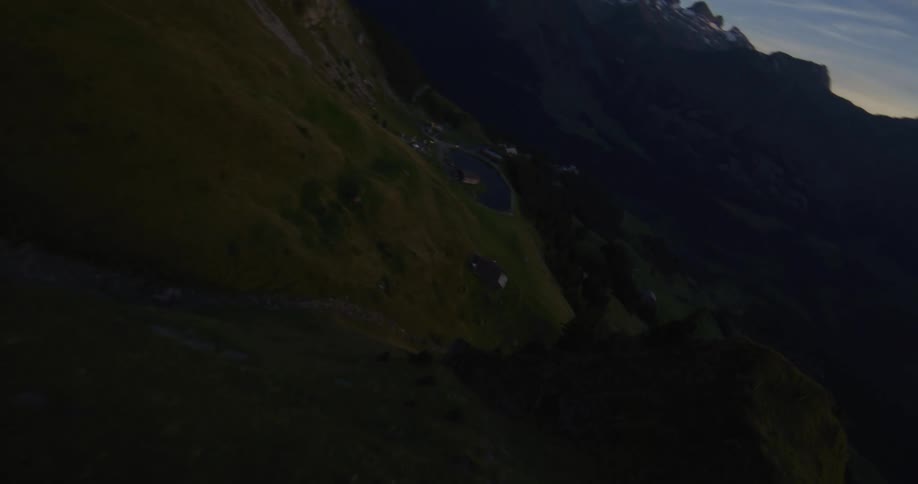 An aerial view that passes over the top of a mountain and there is strong sunlight in the sky