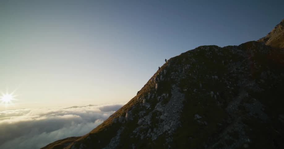 Two people are running across the top of a mountain ridge