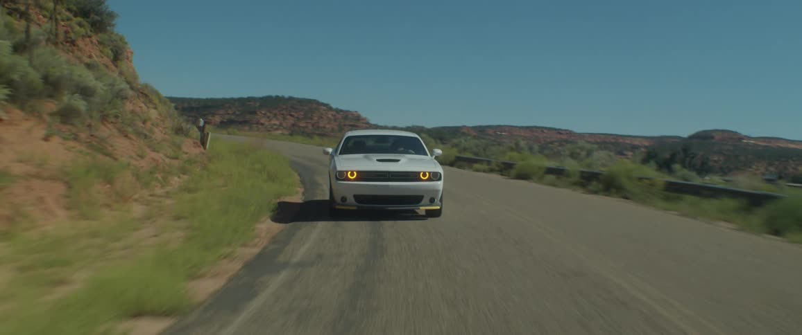 A white car driving on an asphalt rural road