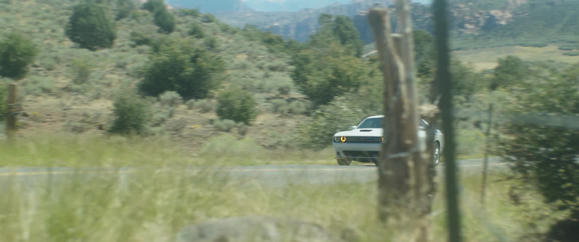 A white dodge car driving in the countryside