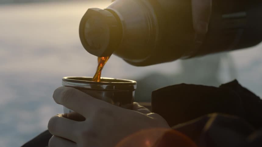 A person pours coffee from a thermos