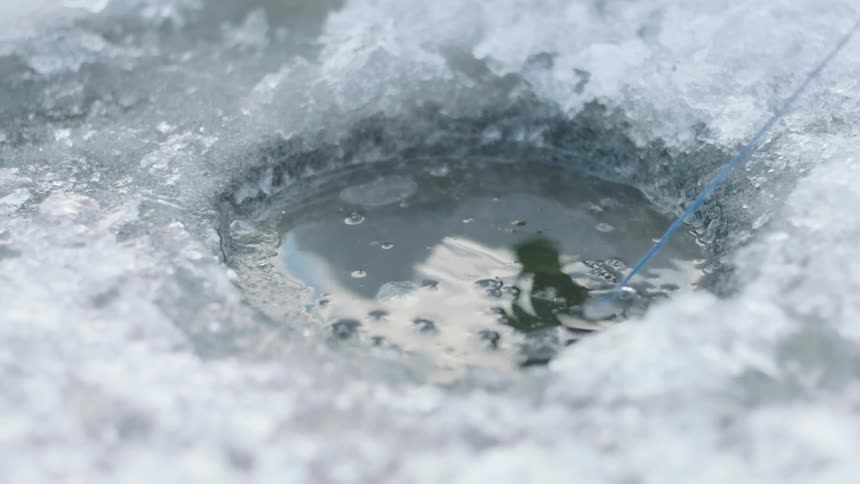 A line pulls a fish out of an icy lake