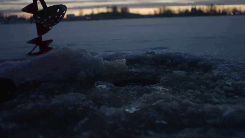 Ice is scooped from a hole in the snowy ground