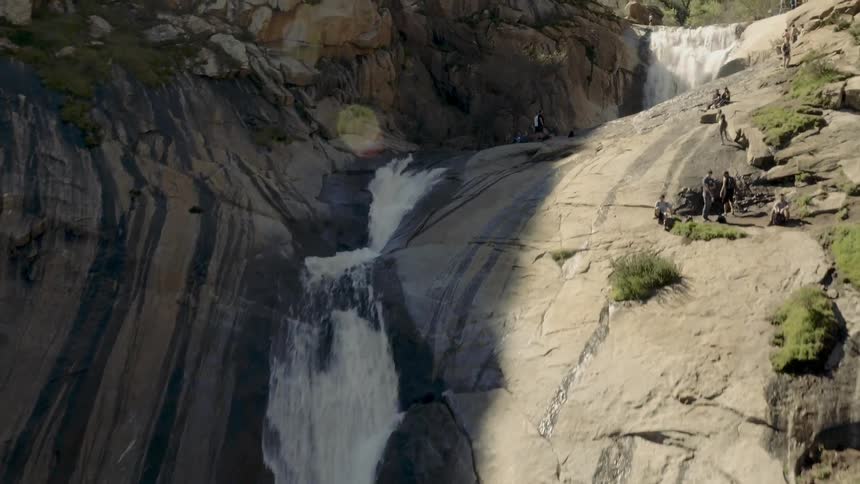 Hikers and tourists crossing over and relaxing at a large waterfall
