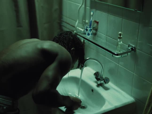 A black teenage boy is washing his teeth and spits on the sink