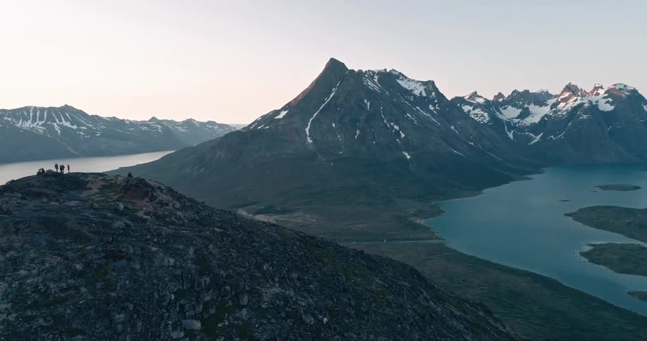 Aerial of a mountain range with snow at the peak during sunset
