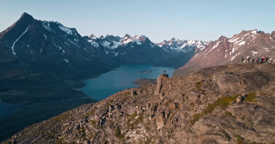 Aerial view of a vast mountain range with a small group of people shown from afar