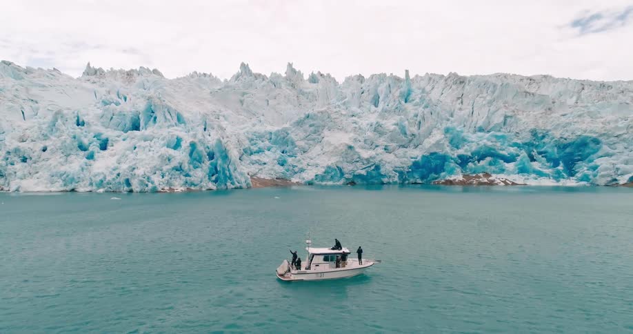 A boat with two people on it drives in the middle of a lake