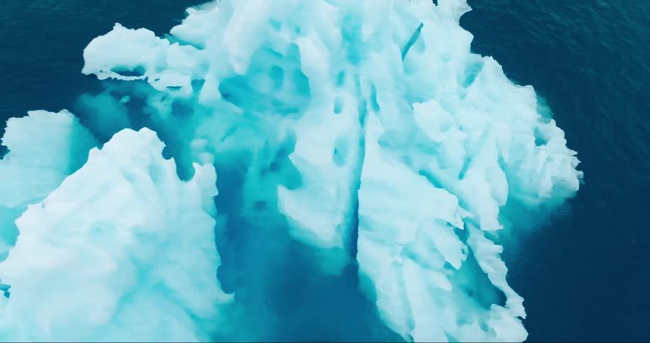 A blue translucent iceberg floating in the arctic ocean