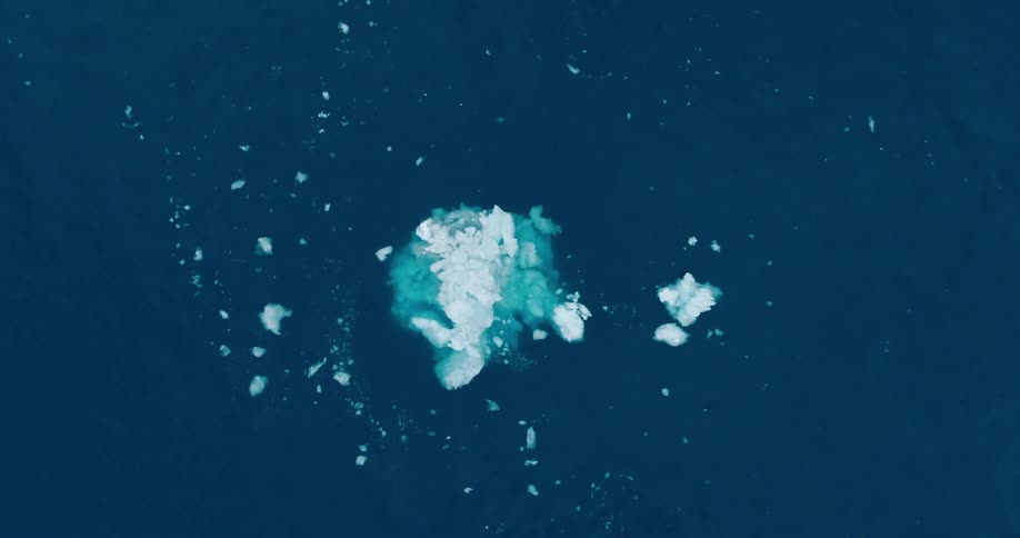 Sea ice floats with a large iceberg in blue ocean water