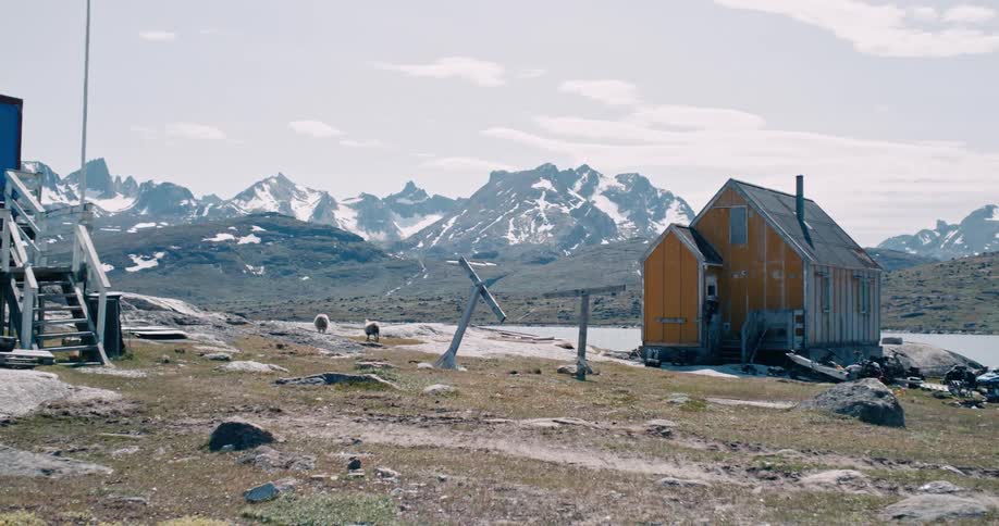 A small building on an highland close to the mountain during winter