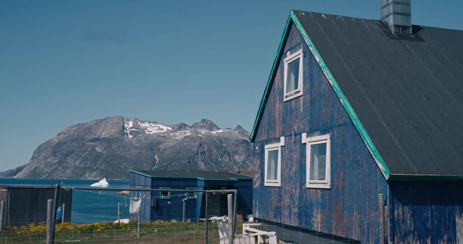 A clip of blue houses in a rural community and a man entering into one of them
