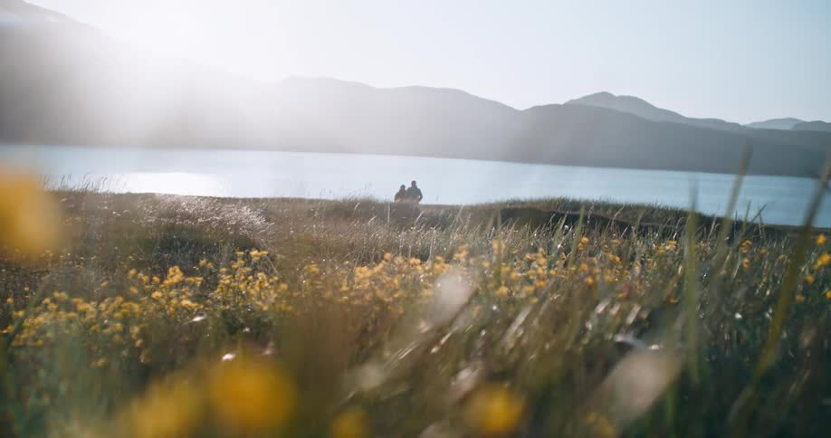 Two people walk towards the lake water