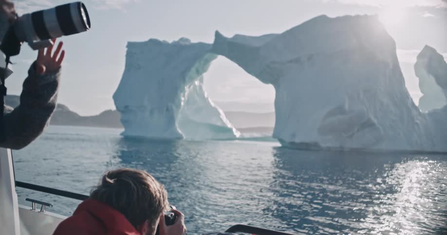 Two people taking pictures of the ice in the middle of the sea