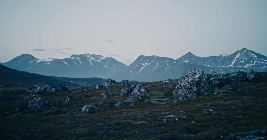 Landscape of a rocky field with a distant snowy mountain range blending rugged textures with serene snowcapped peaks