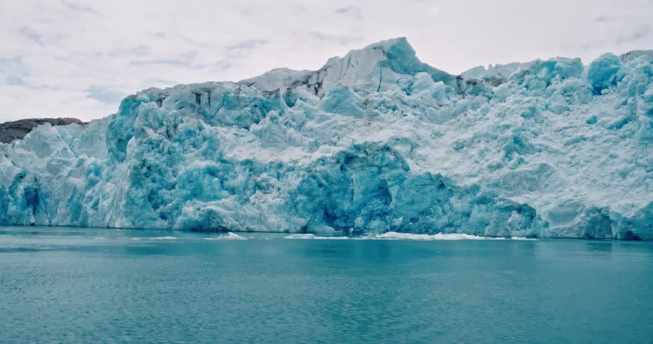 Large iceberg glacier in blue water on a bright day