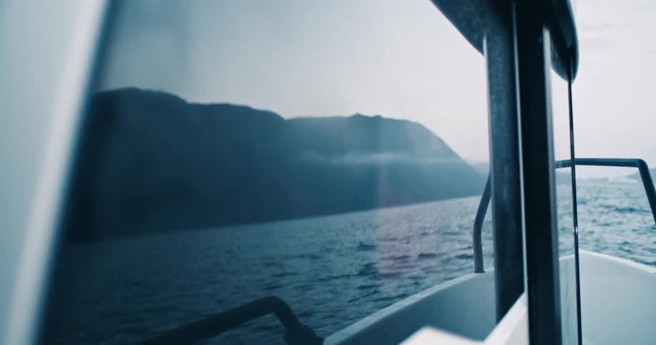 A boat riding on a river close to a mountain