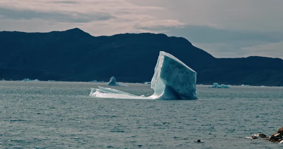 A large iceberg in the arctic sea surrounded by mountains