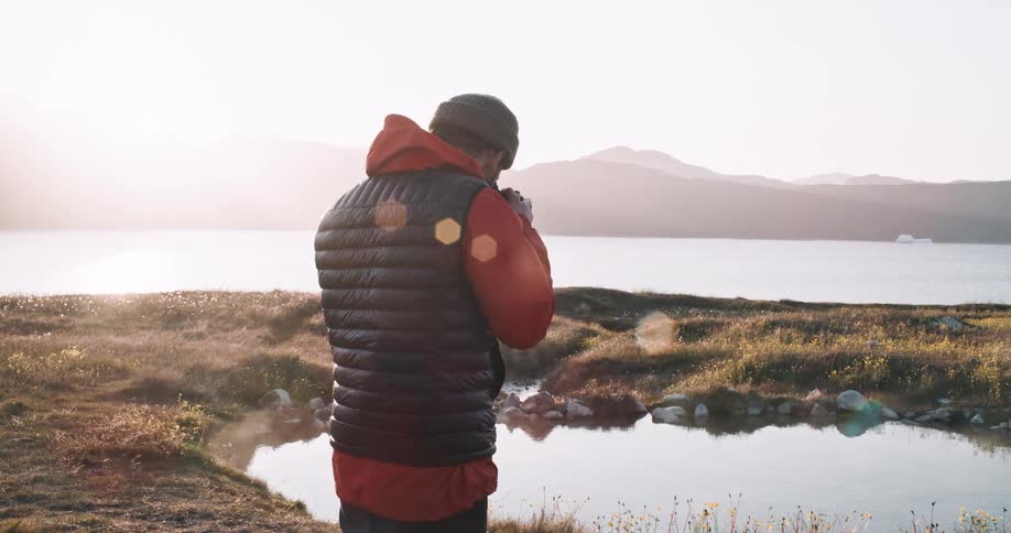 Photographer takes pictures of a small hot spring next to a lake