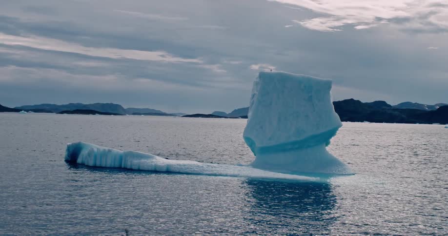 Small iceberg in the midst of the sea on a cloudy day