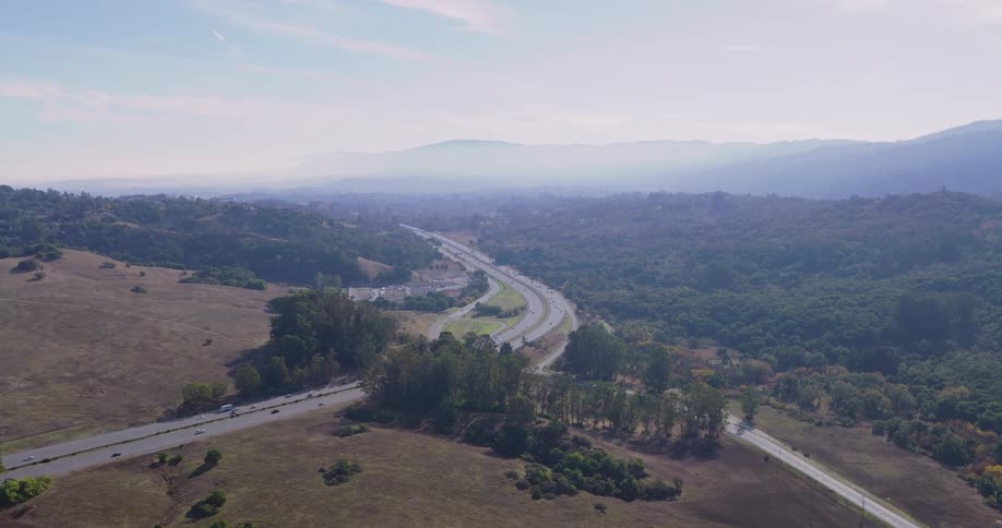 Aerial panorama of a road through natural landscape with trees on a cloudy day