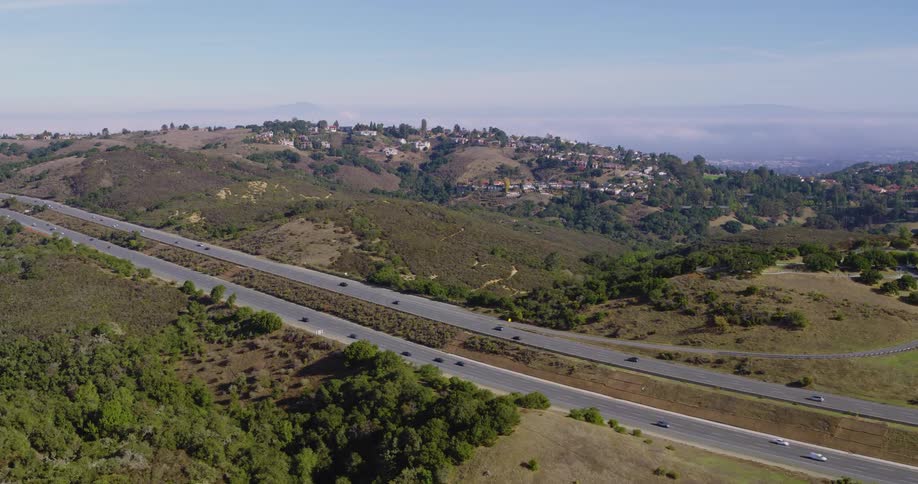 Aerial panorama of a road amidst fields and mountains on a morning