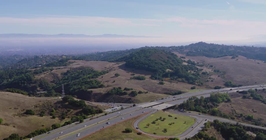 Skyline of a busy highway during the day surrounded by hills