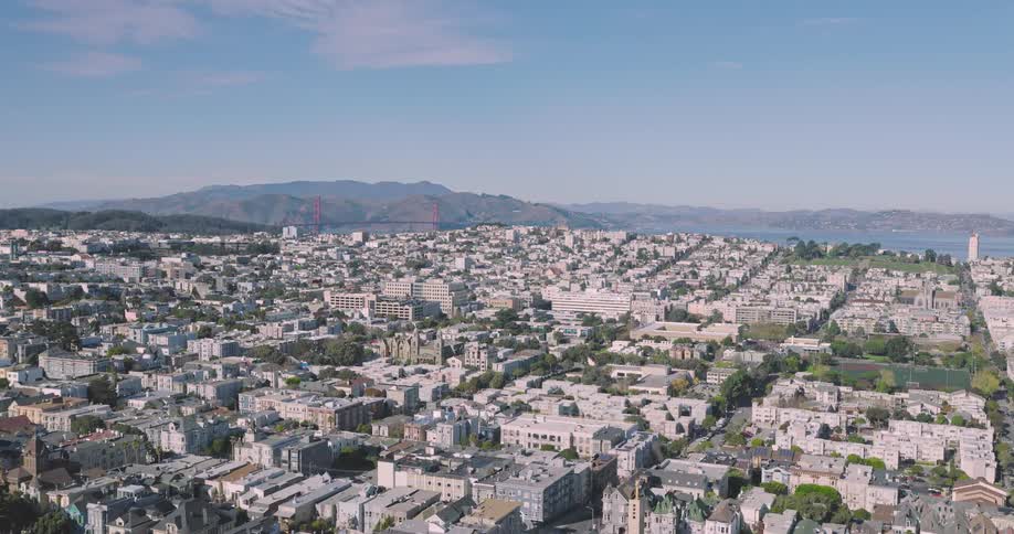 An aerial view of a city with many white colored houses and in the background there are mountains