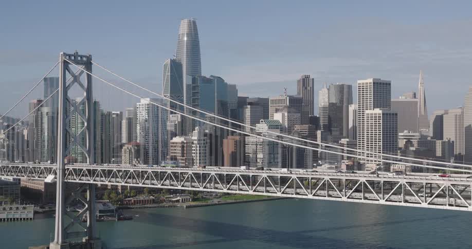 Suspension bridge over the bay with the san francisco downtown city skyline in the background on a bright day