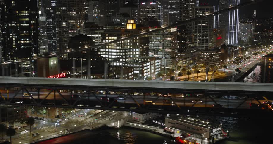 Traffic crosses multi layered suspension bridge near downtown at night