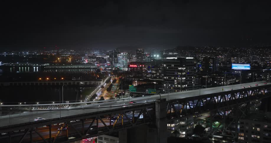 Aerial panorama of a metropolis by a lake with a central bridge at night