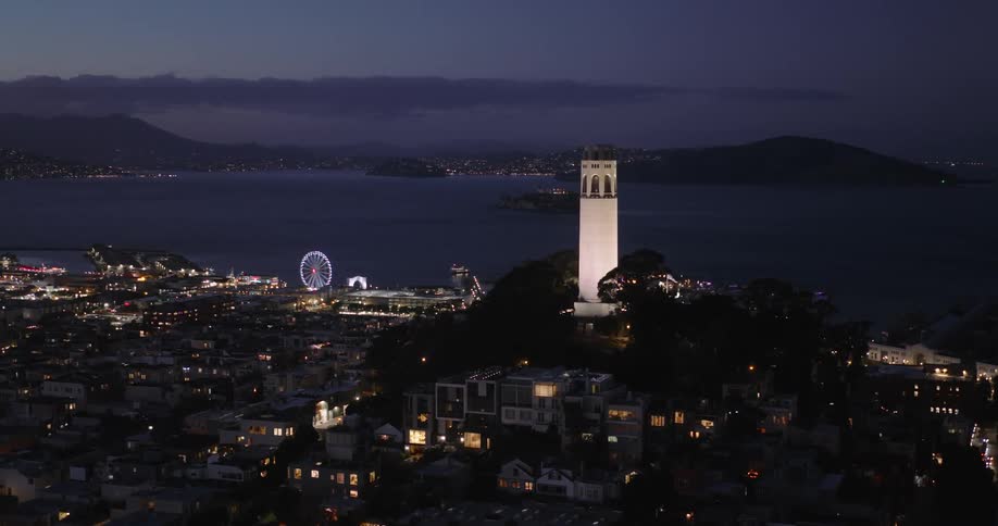 The city glows with electric lights near the shoreline during the night