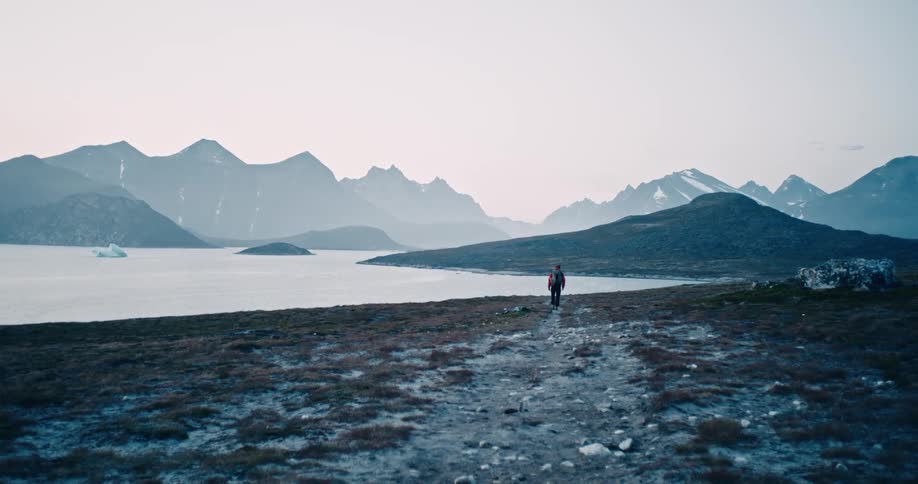 A person walking near the beach with mountains on the horizon