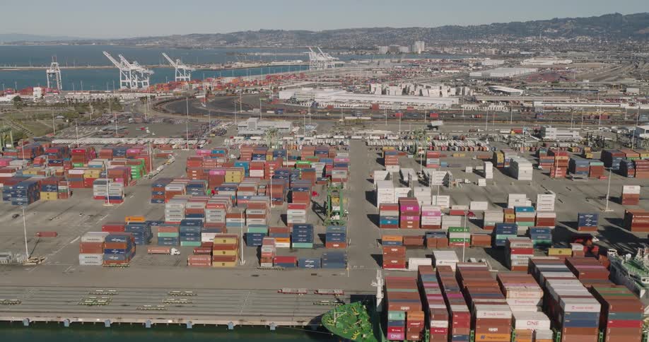 A freight ship is packed with storage containers by the harbor