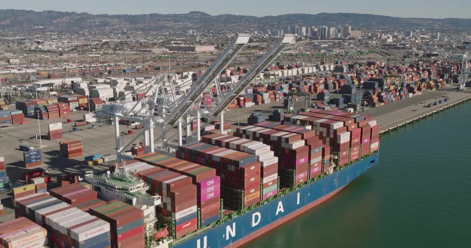 Aerial panorama of a container logistics center with a ship docked at the loaded port and in the distance a metropolis on the horizon