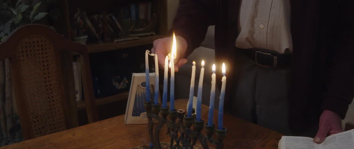 A man is lighting the hanukkah candles
