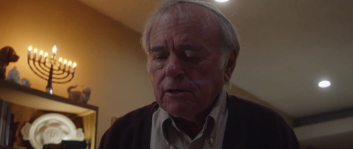 Jewish man praying in front of a menorah at home
