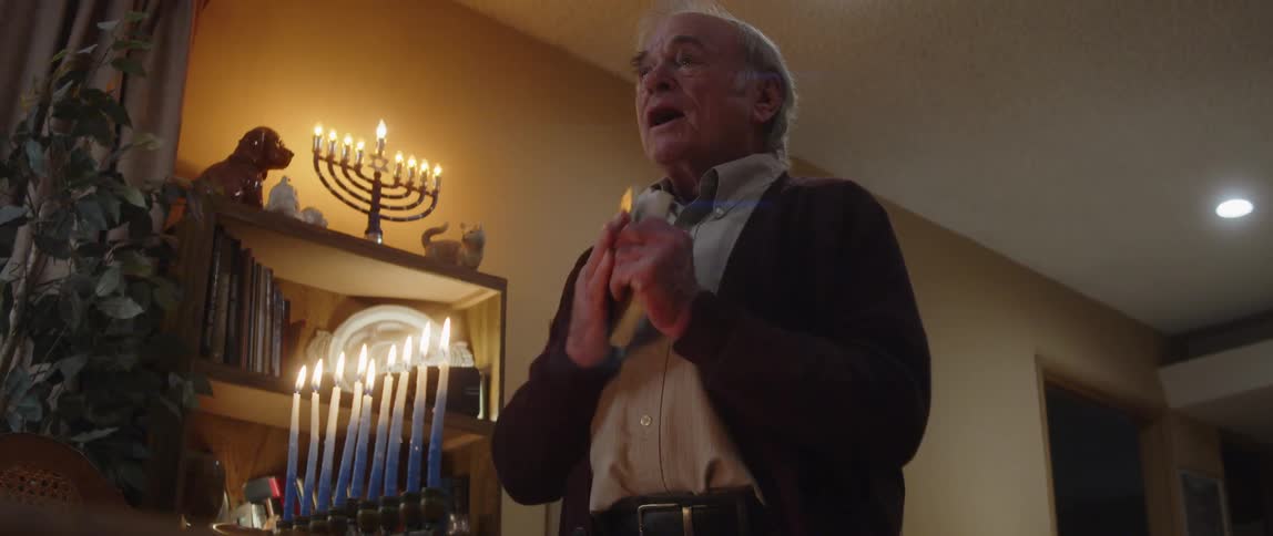 A man is singing in front of hanukkah candles