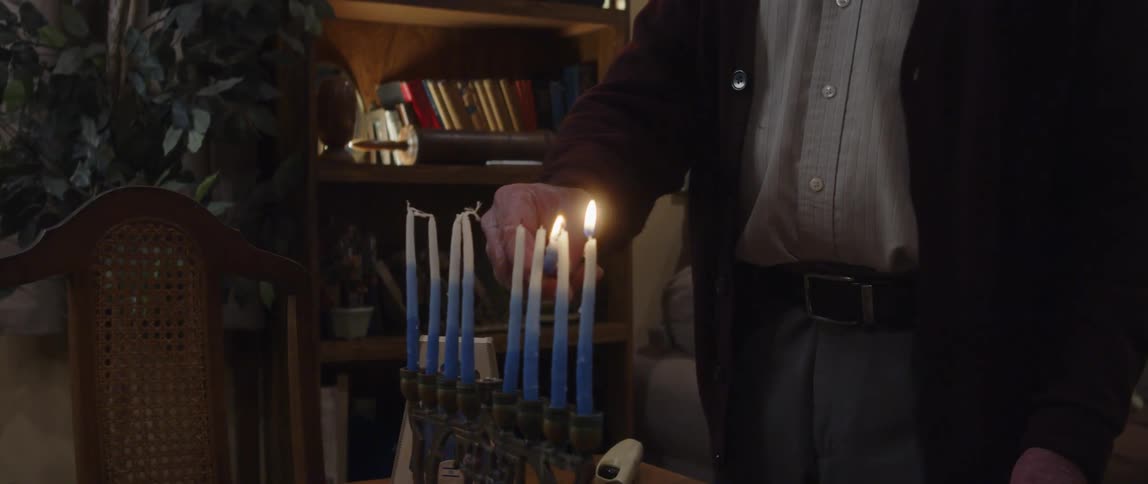 An elderly man lighting candles indoor at night