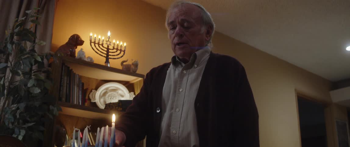 Elderly person praying and lighting candles at a table