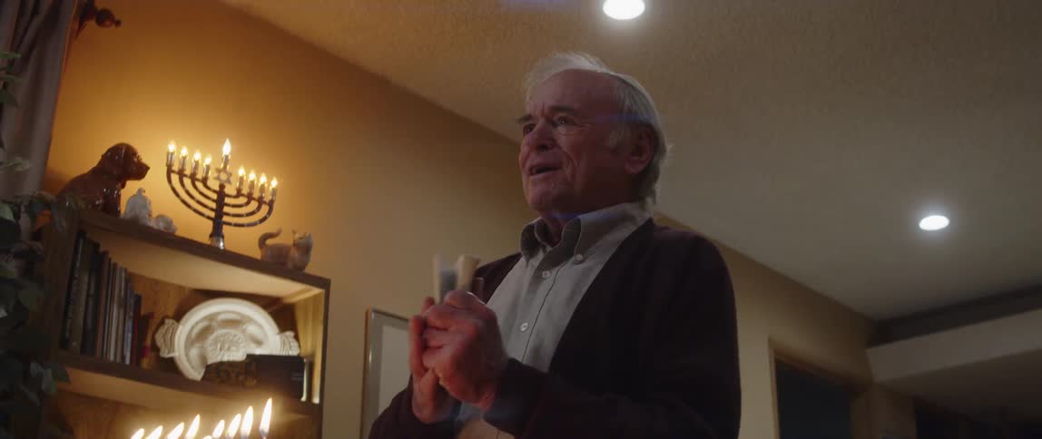 A man is giving a speech in front of hanukkah candles