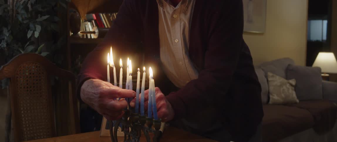 An elderly man setting up series of candles in his living room
