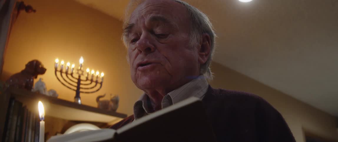 A man is praying by the hanukkah candles